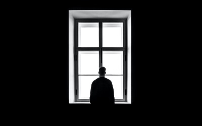 man standing in a window in a dark room