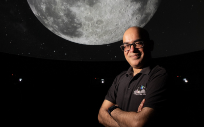 The Open University's Professor Mahesh Anand, standing in front of a Moon image. Photo by Mark Bolam.