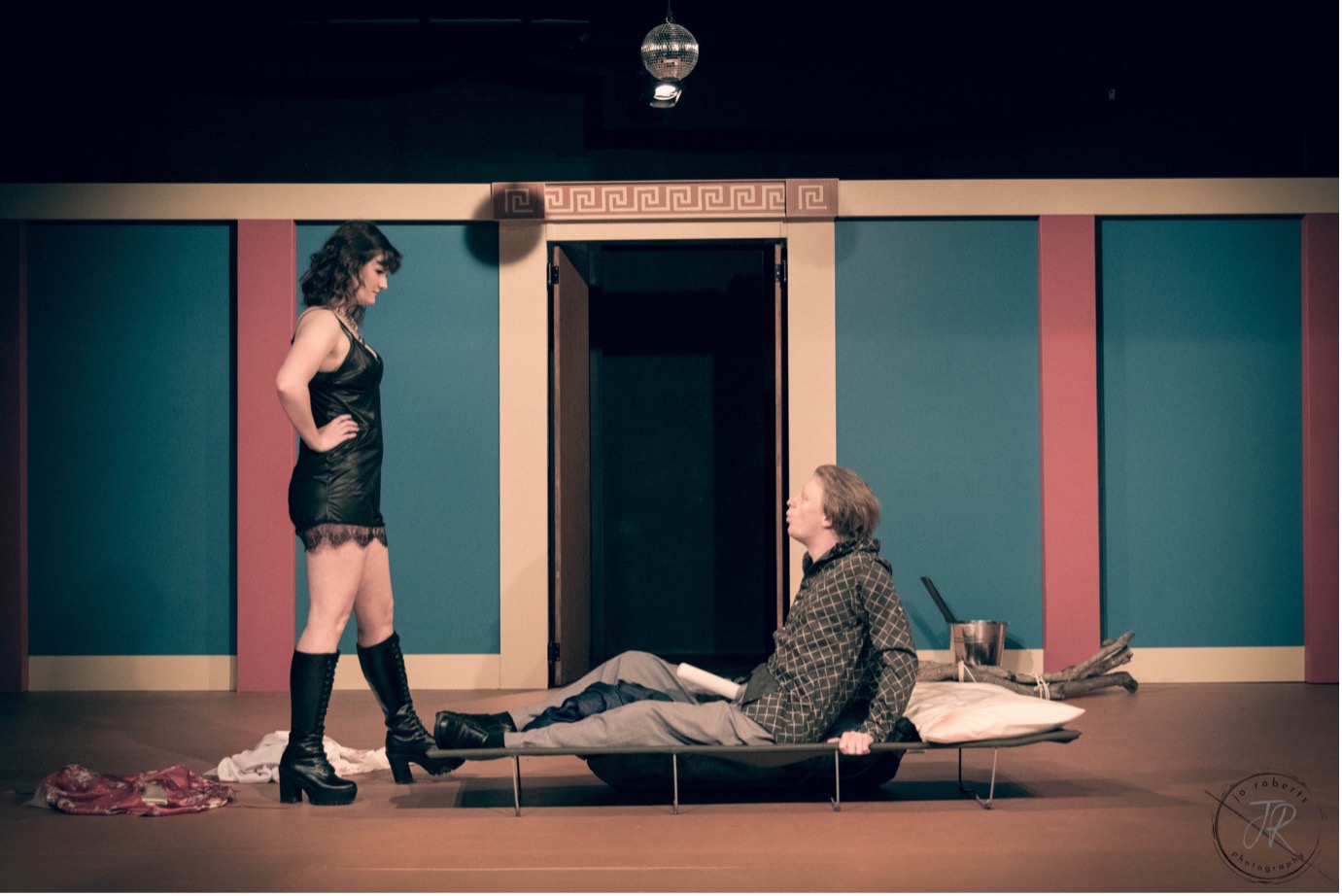 Myrrhine (Grace Callaghan) torments Kinesias (Matthew Collins) by stripping to a short black negligée.