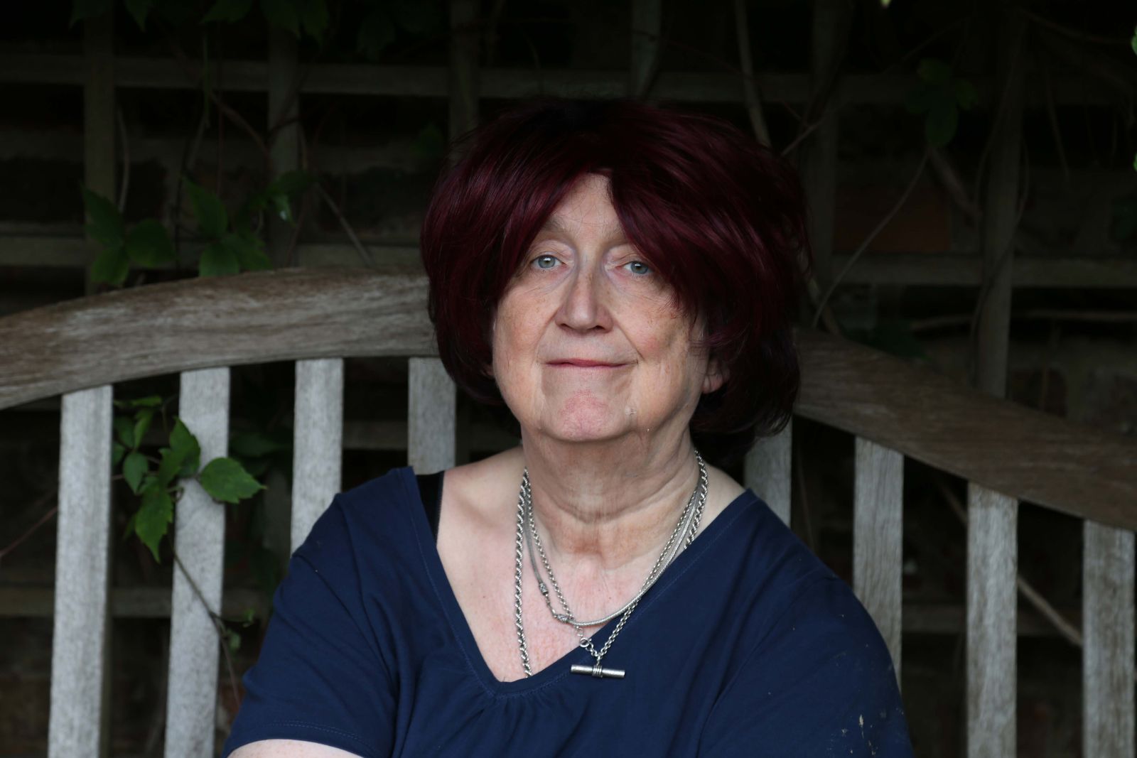 Portrait photograph of the poet Roz Kaveney wearing a blue v-necked top and silver necklaces