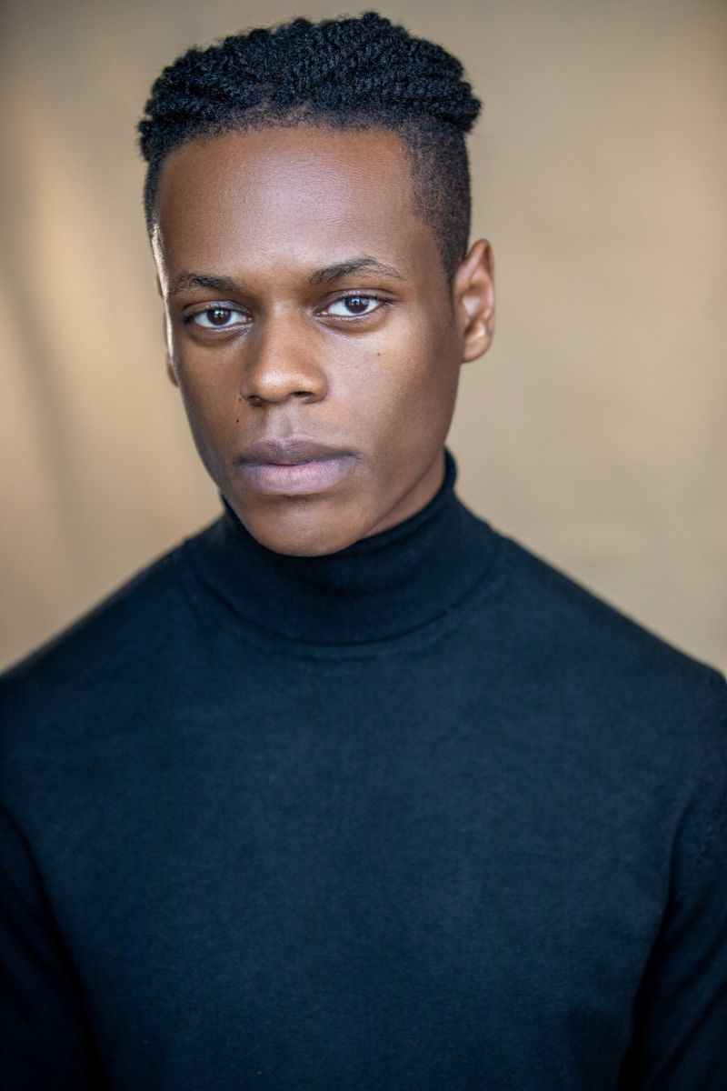 Portrait photo of Kwame Owusu wearing a black turtle-neck sweater and looking straight at camera