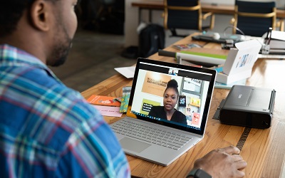 Two professionals speak on a virtual meeting using a laptop