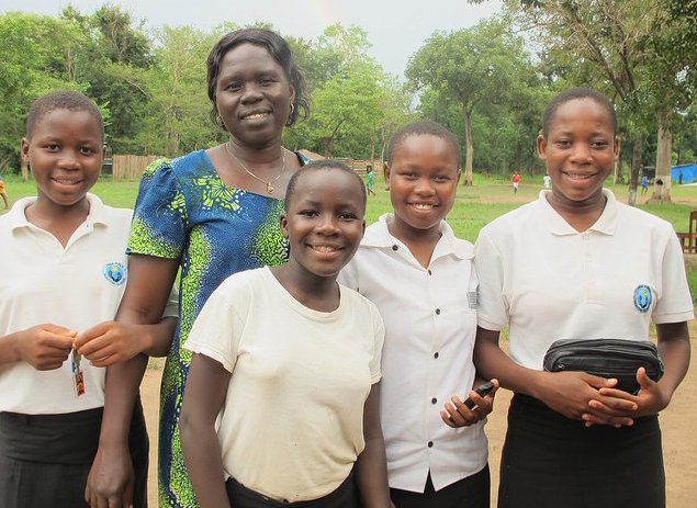 Photo of Ibba School head teacher Vicky Ajidiru with 4 students