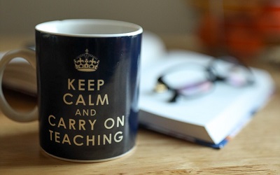 A mug rests on a table and reads 'Keep calm and carry on teaching'