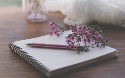 Flowers rest on a pad of paper alongside a pen