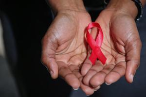 Photo of hands holding pink AIDS awareness day ribbon 