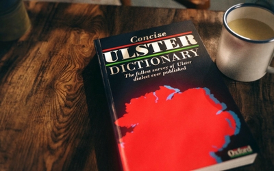 the concise Ulster dictionary sits on a table with a cup beside it