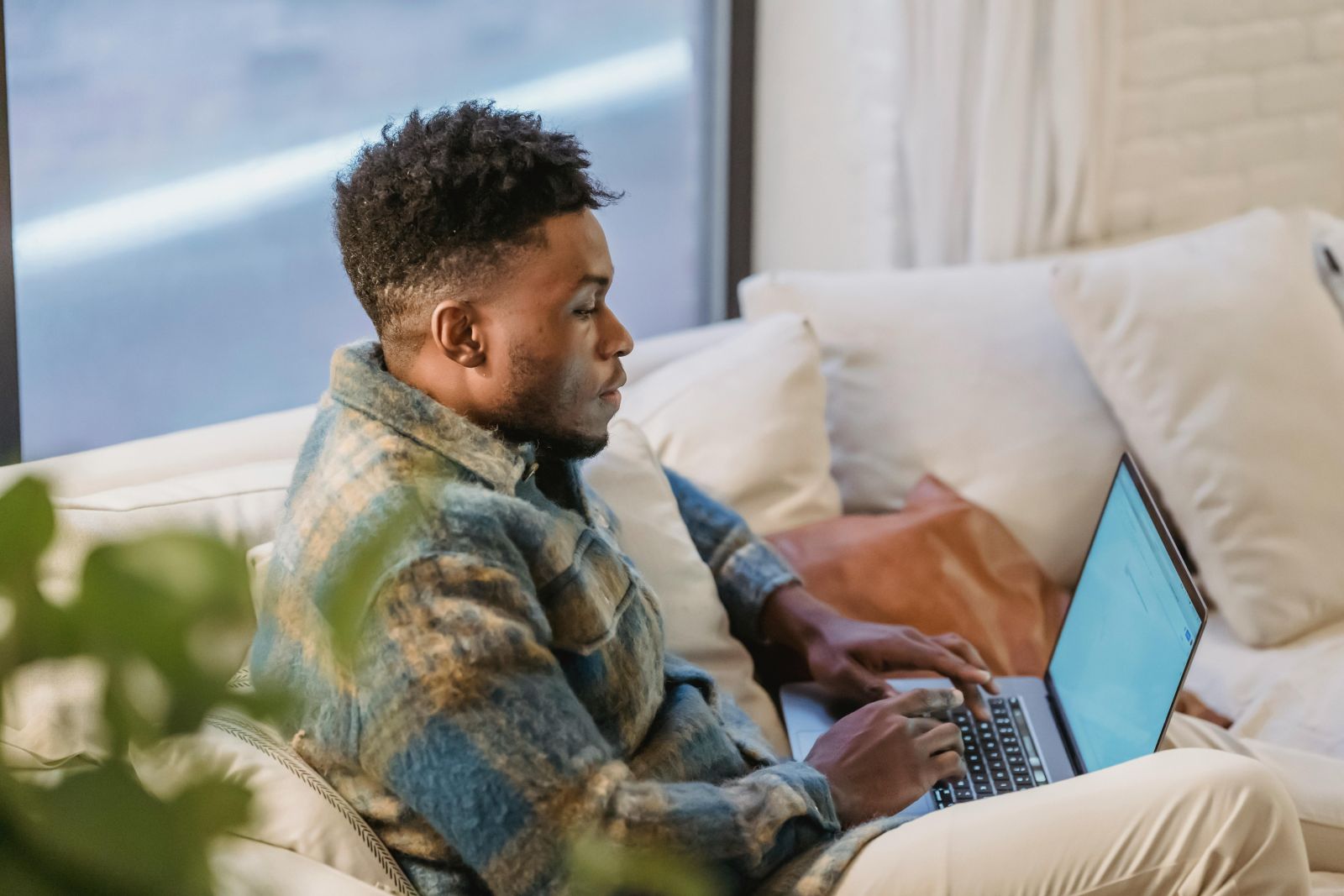 A person sitting on a couch using a computer. Photo by Andres Ayrton: https://www.pexels.com/photo/focused-man-resting-on-sofa-with-laptop-6578430/