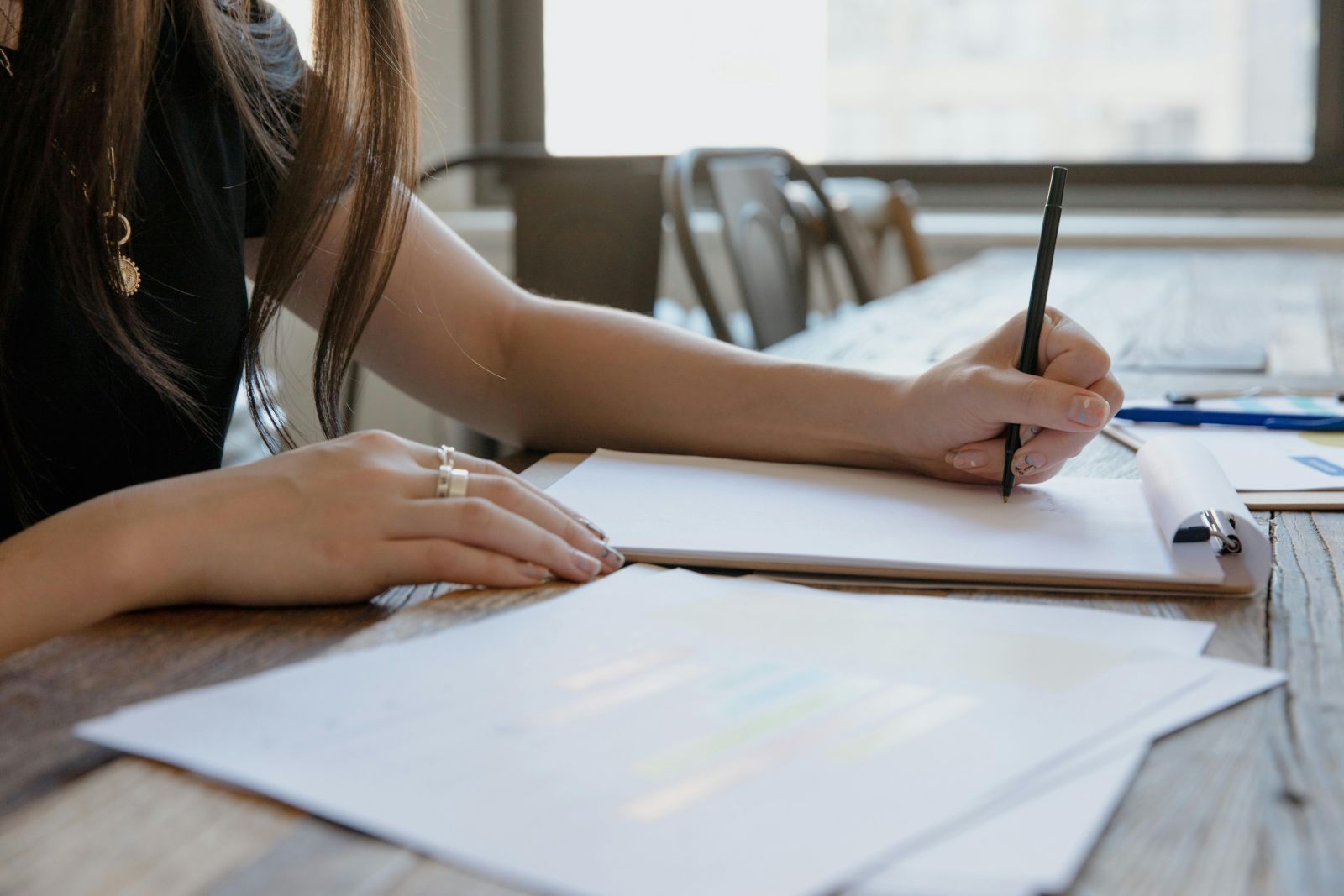 A close-up image of a person writing on a piece of paper. Photo by RDNE Stock project: https://www.pexels.com/photo/a-person-in-black-shirt-writing-on-white-paper-9034711/