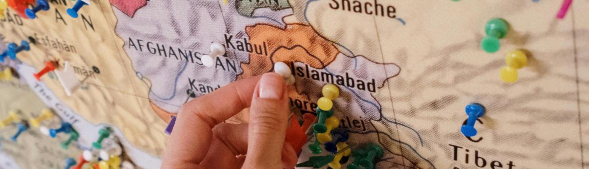 Map of South Asia with a hand placing push pins