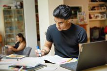 Student working at home with books and a laptop
