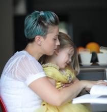 Woman searching on her laptop with a little girl on her lap