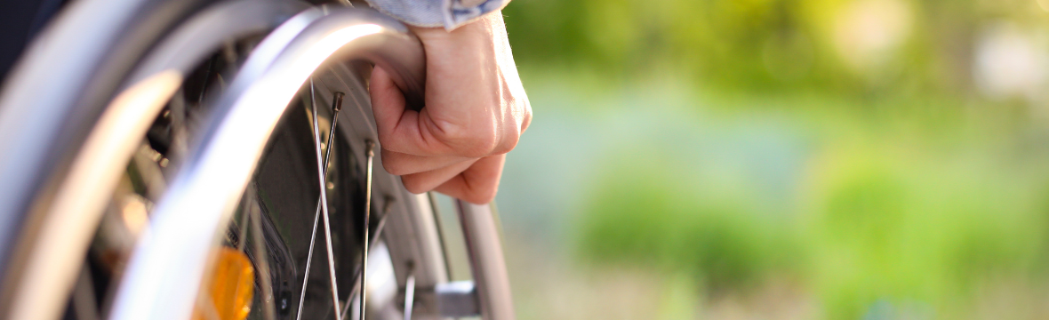 A close up shot of someone's hand moving the wheel on a wheelchair. 