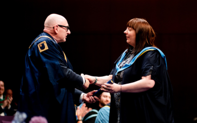 Orlagh is shaking hands on stage as she receives her OU certificate at the Belfast degree ceremony.