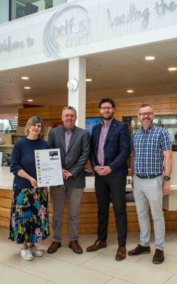 A group of three people stood in the reception area of Belfast Met all showing off their certificates from the carbon literacy training.