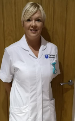 Leona in her OU student nurse uniform standing in front of a wooden door.