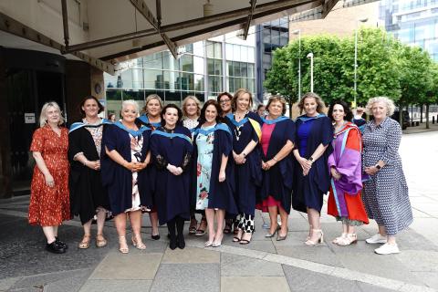 A group of social work graduates standing in their robes posing for a photo
