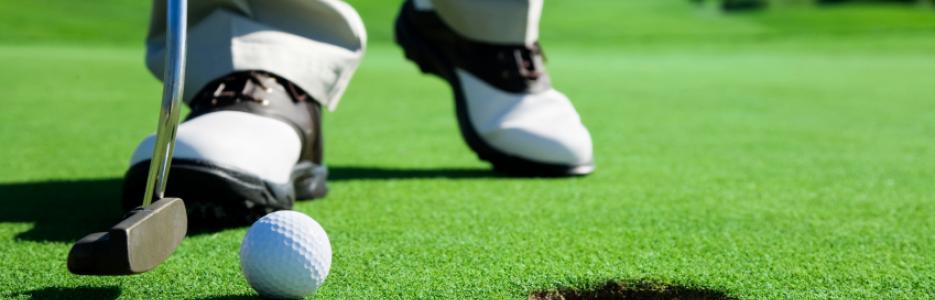 Man putting golf ball into hole