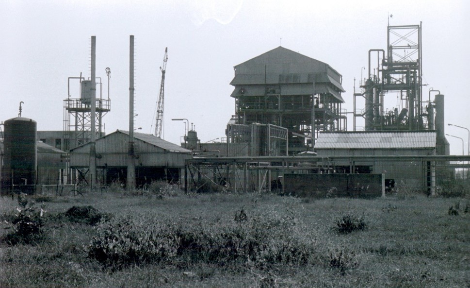 An image of the outside structure of the plant at Bhopal. Two towers stand above and a number of lower structures.