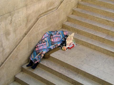 A person sleeping on concrete stairs.