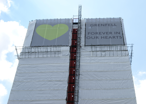 Scaffolding around Grenfell Tower with a picture of a heart on the left side and text saying 'Grenfell, Forever in Our Hearts' on the right.