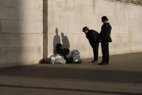 Two police officers speaking to a homeless person.