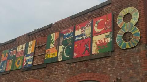 A brick building with 16 flags of various countries with drawings on them.