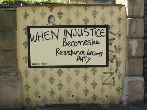 A wall that contains a repeated pattern, and that says 'When Injustice Becomes law Resistance Becomes Duty.