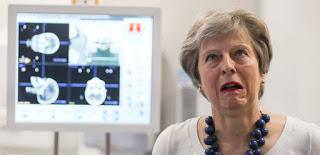 Theresa May making a face infront of a screen displaying medical results.