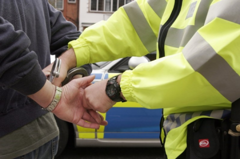 A police officer placing handcuffs on a man.