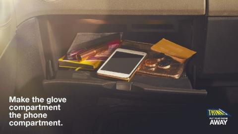 An advert by 'Think! Put the Phone Away!' that displays a glove compartment in a car that contains various items including a mobile phone, with text that states 'make the glove compartment the phone compartment'