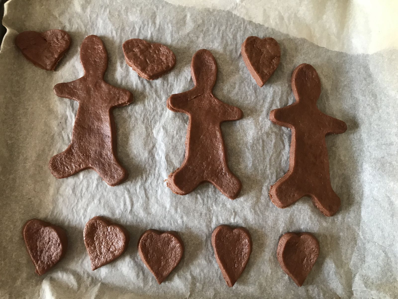 A series of cookies shaped like humans and hearts lie in a row