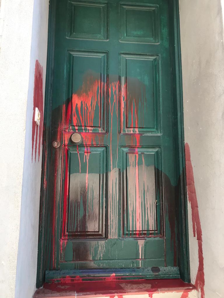 Red paint is splattered across a green front door on Lesvos