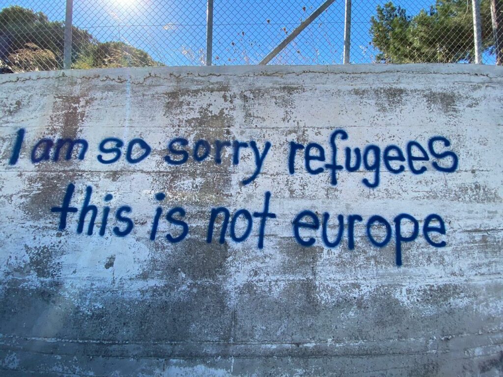 fenced wall with painted text "I am so sorry refugees this is not europe"