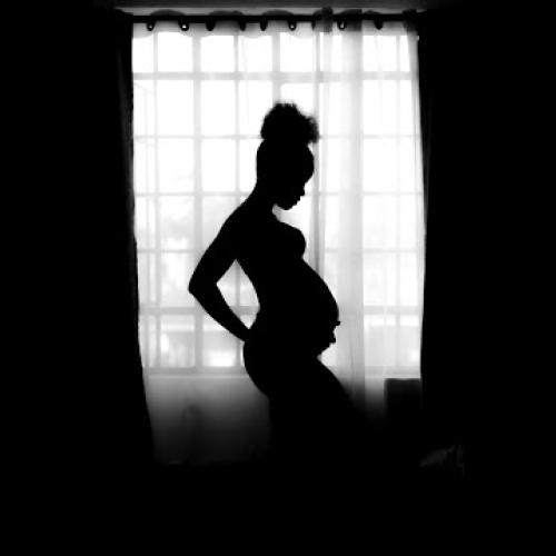 pregnant women standing in the shadow of window light