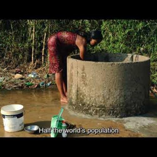 red dressed women lean over a well