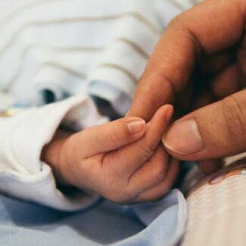 big hand holding new-born baby hand