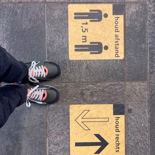 Feet standing next to social distancing signs on the ground