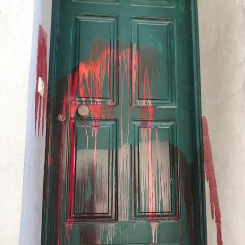 Red paint is splattered across a green front door on Lesvos