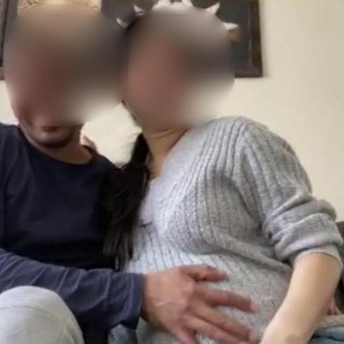 A couple with their faces blurred look at the camera. The man rests his hand sweetly on the woman&#039;s heavily pregnant stomach