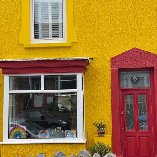A colourful yellow house with a red door in South Wales supporting the NHS and care workers