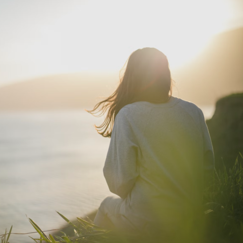 the back of a women sitting on the sea cliff