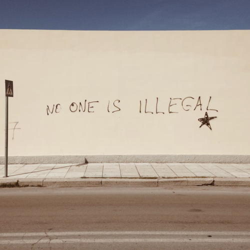 "No one is illegal" written on a white wall