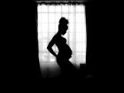 pregnant women standing in the shadow of window light