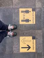 Feet standing next to social distancing signs on the ground