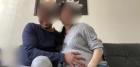 A couple with their faces blurred look at the camera. The man rests his hand sweetly on the woman&#039;s heavily pregnant stomach