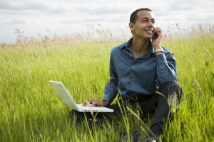 Man using laptop sitting in a field
