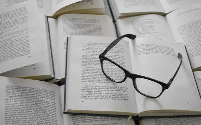 Photo of a pair of spectacles on books, by Tamara Gak on Unsplash. 