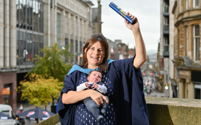 Nursing graduate Nicola Hehir holding her baby and an Open University scroll - photo by Julie Howden.