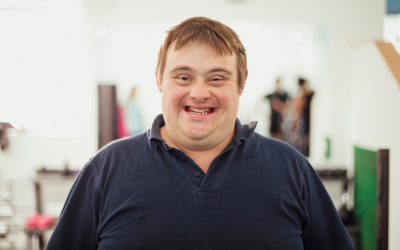 A man with Down's syndrome, facing directly towards the camera, and smiling.